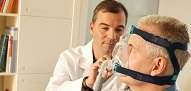 Neumólogo/médico que muestra el dispositivo CPAP del paciente con apnea del sueño y la máscara para dormir utilizada para la terapia del sueño en el hogar